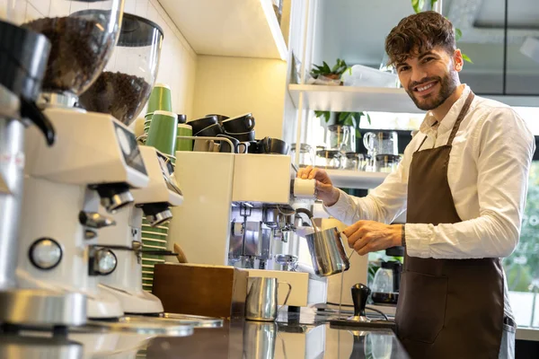 Bearded man barista brewing coffee in cafe enjoying his work making hot beverage