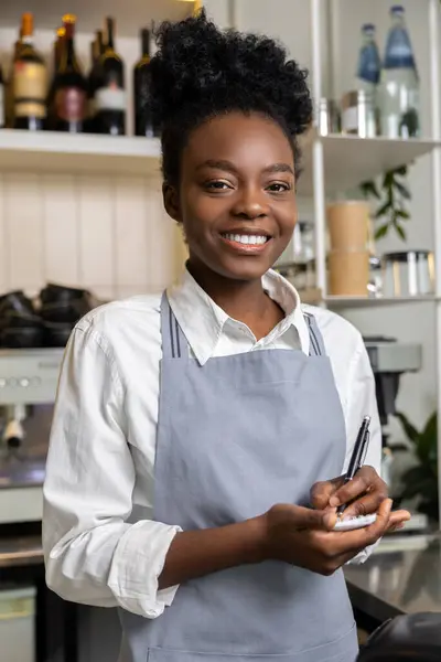 stock image Smiling woman waiter standing near counter taking client order