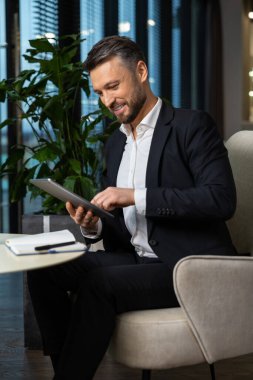 Hoşnut hissediyorum. Ofiste çalışan, elinde tabletle pozitif genç bir yönetici.