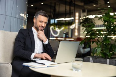 Çalışıyorum. Dizüstü bilgisayarda çalışan şık, sakallı bir adam.