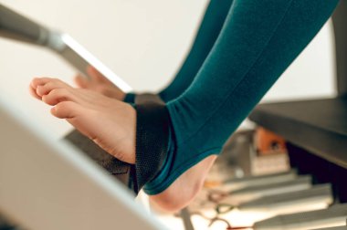 Bilinmeyen kadın bacakları tüm vücut pilates çalışması için reformist makinesinde.