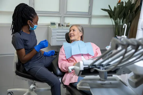 中年妇女坐在医疗中心的牙科椅子上 专业医生在为她修牙 — 图库照片