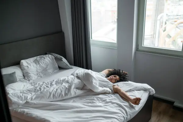 Esniyorum Esmer Genç Adam Yatağında Uzanıyor Uyuduktan Sonra Geriniyor — Stok fotoğraf