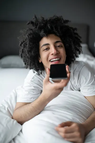 Voice message. Young man lying in bed and recording a voice message