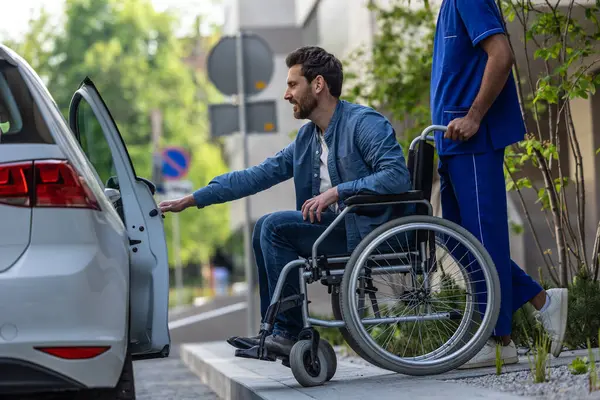 Getting in car. Dark-haired man on a wheelchair opening a car door