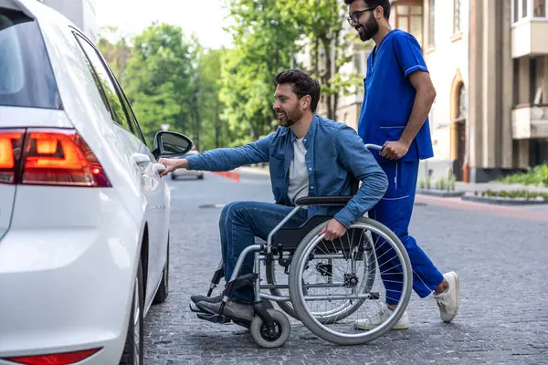 Car for disabled man. Man in a wheelchair opening a car door