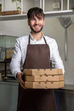Elinde pizza kutuları olan beyaz bir adam Pizza Cafe 'de çalışıyor. Ekspres servis ve siparişleri yönetiyor.