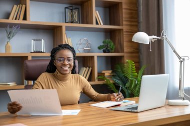 Rastalı, kendine güveni tam bir serbest çalışan kadın evde online iş için dizüstü bilgisayar kullanıyor.