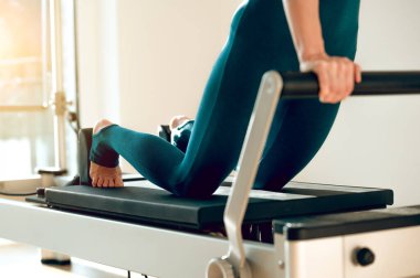 Esneklik ve zarafetle pilates reformatörü kullanan tanınmayan fit bir kadın.