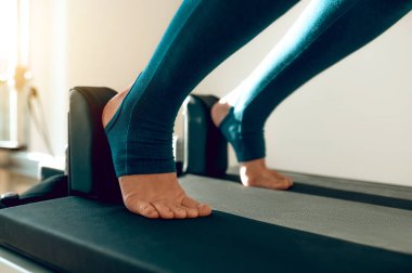 Tanımlanamayan wman, egzersiz deneyimini geliştirmek için Pilates yenilikçisine bacak esnetiyor.