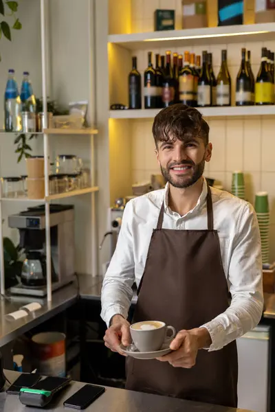 カフェカウンターでコーヒーカップを持ち お客様に効率的なサービスを提供することに満足のいくひげ男 — ストック写真