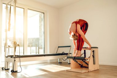 Spor salonundaki sporcu kadın yoga stüdyosundaki yenilikçi makinede egzersiz yapıyor.