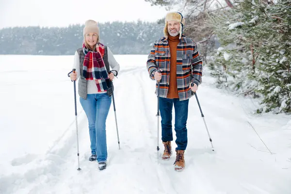 Winter activity. Couple on a walk with scandinavian sticks