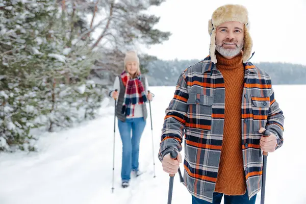 Winter activity. Couple on a walk with scandinavian sticks