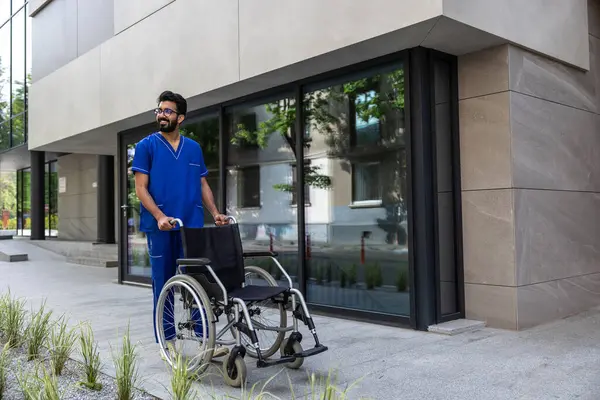 Male Nurse Positive Male Nurse Blue Doctors Overall Carrying Wheelchair — Stock Photo, Image