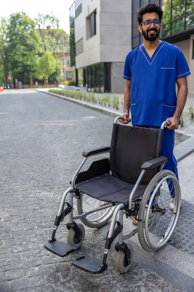 Man Wheelchair Positive Male Nurse Blue Doctors Overall Carrying Wheelchair — Stock Photo, Image