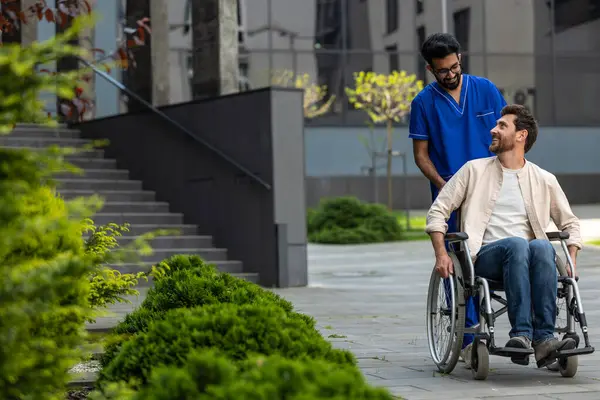 Good mood. Male nurse rolling a wheelchair with patient and both feeling good