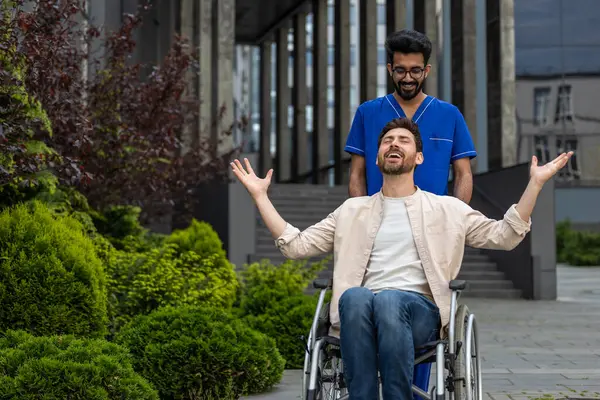 Good mood. Male nurse rolling a wheelchair with patient and both feeling good