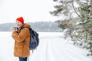 Sıcak çay. Karlı bir ormanda elinde termosla bir adam