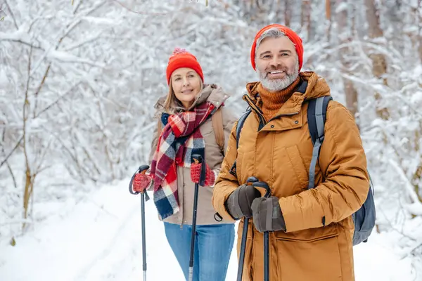 Good mood. Man and woman with scandinavian sticks in a winter forest looking enjoyed