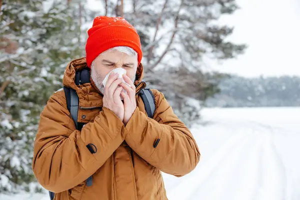 Got sick. Man in a winter forest looking sick and got running nose