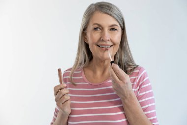 Dudak parlatıcısı. Oldukça olgun, uzun saçlı, dudak parlatıcı kullanan ve gülümseyen bir kadın.