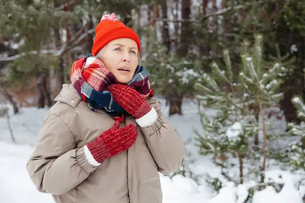Caught cold. Mature woman in warm clothes having sore throat