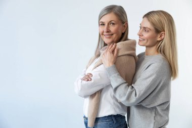 Şefkat. Sarışın genç bir kadın annesine sarılıyor ve huzurlu görünüyor.