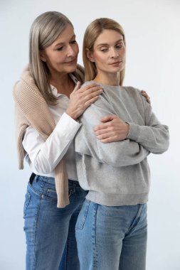 Şefkatli anne. Gri saçlı güzel bir kadın kızına şefkatle sarılıyor.