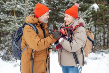 Şefkatli koca. Bir adam kış ormanında yürürken karısının ellerini ısıtır.