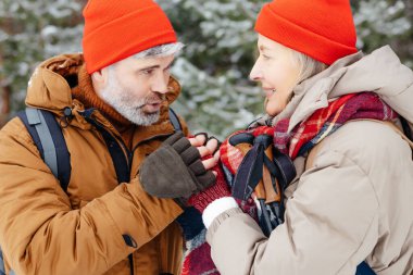 Şefkatli koca. Bir adam kış ormanında yürürken karısının ellerini ısıtır.