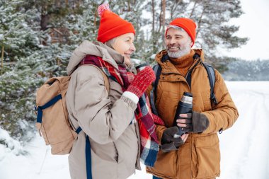 Sıcak çay. Kış ormanında çay içen gülümseyen olgun bir çift.