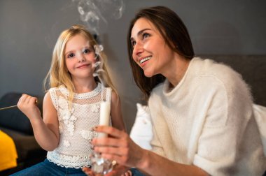 Otel odasında aromalı mumla mutlu anne ve kız.