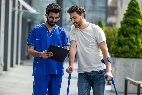 Walk Together Man Crutches Male Nurse Talking Friendly Walk — Stock Photo, Image