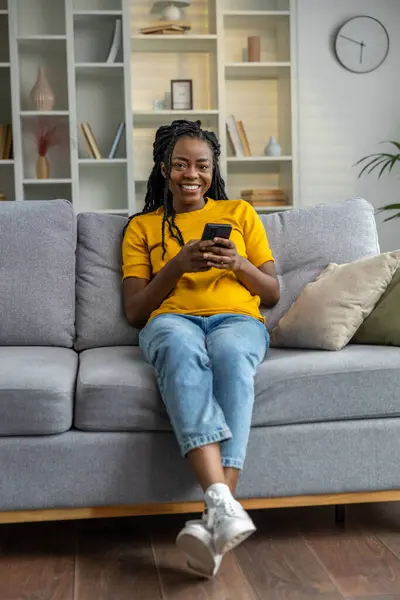 Senyum Gadis Berkulit Gelap Duduk Sofa Dengan Telepon Tangan — Stok Foto