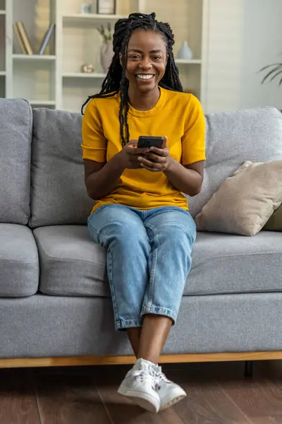 Senyum Gadis Berkulit Gelap Duduk Sofa Dengan Telepon Tangan — Stok Foto
