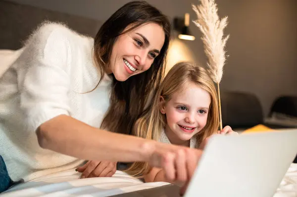 Mulher Atraente Com Filha Pequena Usando Laptop Para Entreter Quarto — Fotografia de Stock