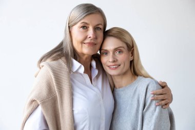 Anne ve kızı. Anne ve kızı beyaz bir arka planda yan yana duruyorlar.