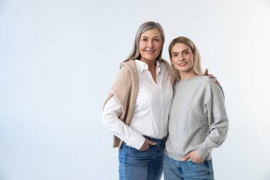 Anne ve kızı. Anne ve kızı beyaz bir arka planda yan yana duruyorlar.