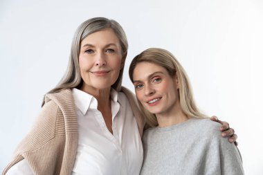 Anne ve kızı. Anne ve kızı beyaz bir arka planda yan yana duruyorlar.