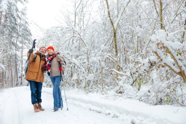 Ormanda yürü. Sırt çantalı ve ormanda İskandinav sopalı iki kişi.