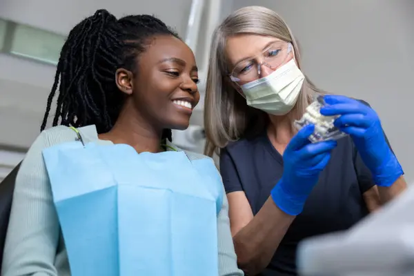 Kadın Dişçi Klinikteki Hastasına Takma Diş Gösteriyor — Stok fotoğraf