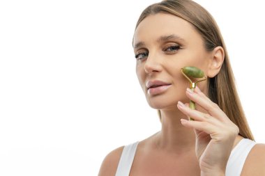 Yüz masajı. Sarışın kadın silindirle yüz masajı yapıyor.