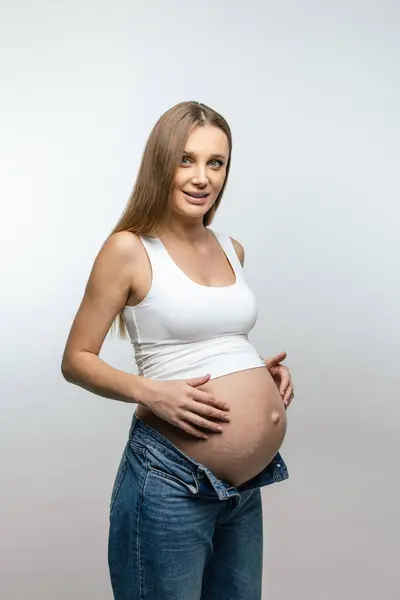 怀孕的女人穿着牛仔裤和白衬衫的年轻孕妇 — 图库照片