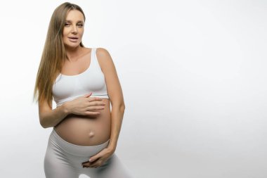 Hamilelik. Beyaz elbiseli, uzun saçlı, hamile, beyaz bir kadın.