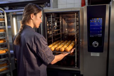 Üniformalı genç bir fırıncının portresi fırında taze ekmek pişiriyor.