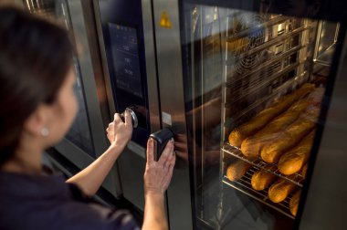 Üniformalı genç bir fırıncının portresi fırında taze ekmek pişiriyor.