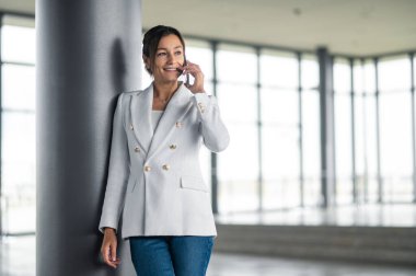 Modern iş kadını. Elinde telefon olan hoş, şık bir kadın.