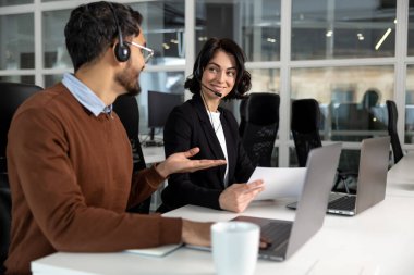 Genç ofis çalışanları birlikte çalışmak için dizüstü bilgisayar kullanıyor.
