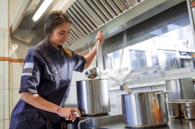 Çorba pişiriyorum. Genç bir kadın mutfakta çorba pişiriyor ve elinde bir kepçeyle